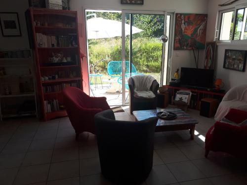 un salon avec une table, des chaises et une télévision dans l'établissement Ty Chaméléon, à Trégastel