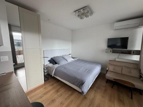 une chambre avec un lit, une télévision et une chaise dans l'établissement Beau Studio avec belle terrasse au centre ville de Nice, à Nice