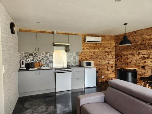 a kitchen with white cabinets and a couch at Le Petit Gîte 15140 in Sainte-Eulalie