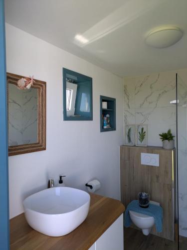 a bathroom with a large white tub and a toilet at Gerestylde vintage caravan "Zee" met luxe badkamer bij "de Kapitein" in 't Horntje