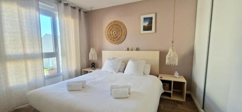 une chambre avec un grand lit blanc et une fenêtre dans l'établissement Maison cosy proche du centre-ville, à Vannes