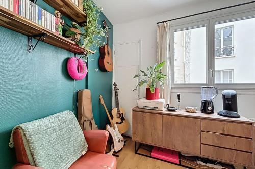 un salon avec des guitares au mur et une chaise dans l'établissement Cosy duplex close to Notre Dame, à Paris