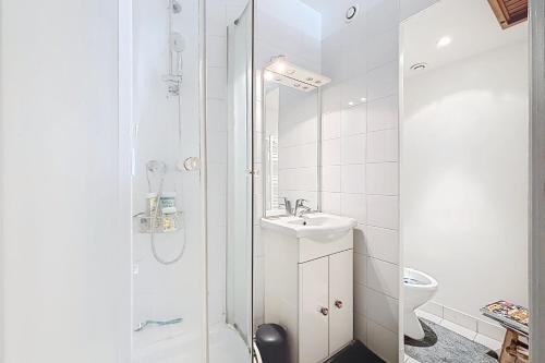 une salle de bain blanche avec un lavabo et une douche dans l'établissement Cosy duplex close to Notre Dame, à Paris