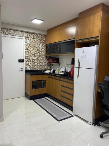 a kitchen with a white refrigerator and wooden cabinets at 10 minutos do Aeroporto GRU, Ar Condicionado, vaga coberta, vista livre in Guarulhos