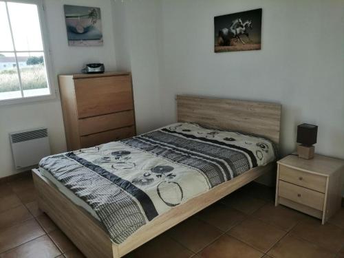 une chambre avec un lit, une commode et une fenêtre dans l'établissement MAISON individuelle près des PLAGES, à Saint-Hilaire-de-Riez