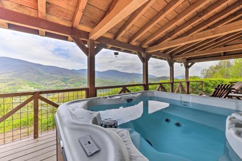 a hot tub on a deck with a view of mountains at True Log Cabin with Game Room, Year-Round Views in Waynesville