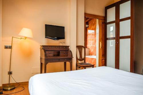 a bedroom with a bed and a desk and a television at Indiana Boutique Hotel in Llanes