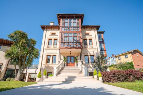 a large white building with stairs in front at Indiana Boutique Hotel in Llanes
