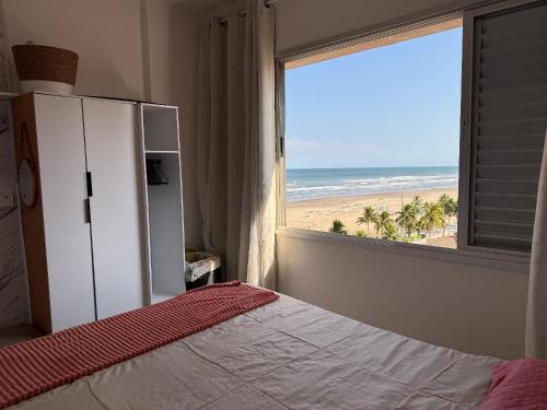 a bedroom with a bed and a view of the beach at Kitão Frente Mar Na Tupi! in Samaritá