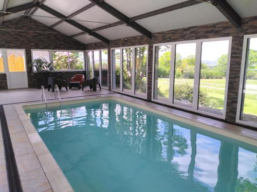 a swimming pool in a house with windows at Le champ bourdon in Saint-Maur-des-Bois