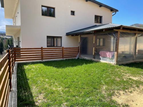 a house with a fence and a green yard at Briza de Munte in Colibiţa