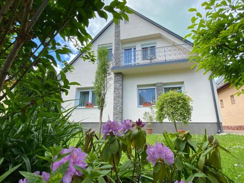 a white house with purple flowers in front of it at Linda ház in Siófok