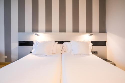 two beds in a room with striped walls at Indiana Boutique Hotel in Llanes