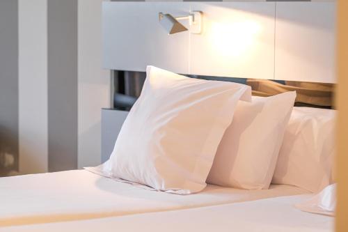 a bed with white pillows on top of it at Indiana Boutique Hotel in Llanes