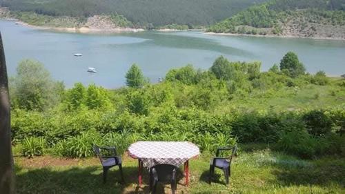 a table with three chairs and a view of a lake at Vikendica Vidikovac na Zavojskom jezeru in Pirot