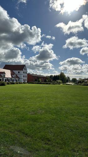 a large grass field with a building and clouds in the sky at Ferienapartment Janow in Spantekow