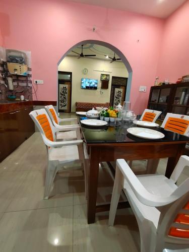 a dining room with a table and white chairs at Sneh Homestay in Ayodhya