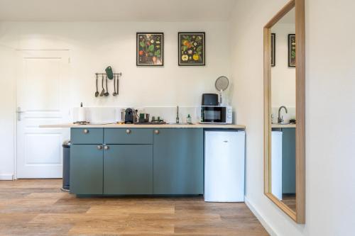 La cuisine est équipée de placards bleus, d'un lavabo et d'un miroir. dans l'établissement Douceur de Loire - Maison 4 personnes, à Savonnières