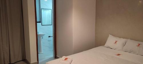 een slaapkamer met een wit bed en een douche bij Hostal Pulpos in Bombiso