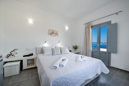 a white bedroom with a bed with towels on it at Pancratium Villas & Suites in Akrotiri