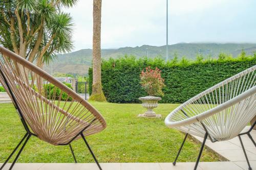 two white chairs sitting in a yard with a vase at Indiana Boutique Hotel in Llanes