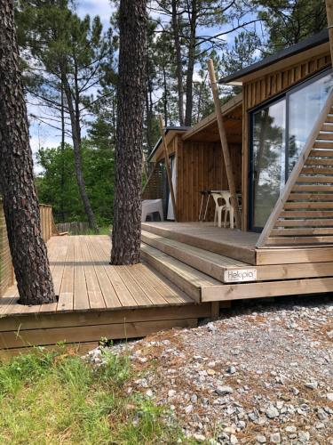 a wooden deck next to two trees in front of a cabin at Manoir de Champvert in Les Vans