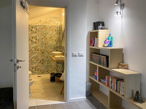 baño con aseo y estante para libros en Nest Guesthouse, en Castelnuovo del Garda