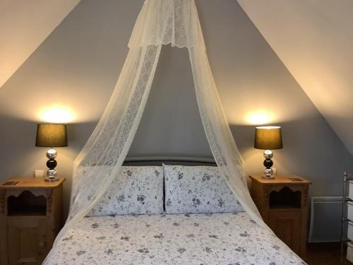 une chambre avec un lit à baldaquin avec deux lampes dans l'établissement Romantic Cottage, à Vire