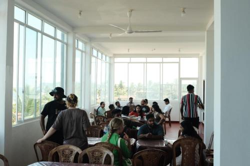 eine Gruppe von Personen, die in einem Zimmer mit Fenstern sitzen in der Unterkunft Koala Backpackers in Trincomalee