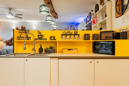 a kitchen with white cabinets and a yellow wall at Wellness Apartment Medusa in Hamr na Jezeře