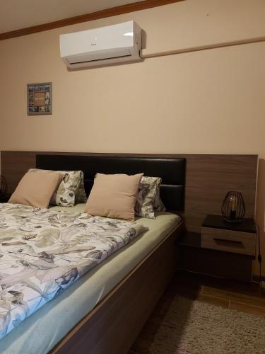 a bedroom with a bed with a air conditioner on the wall at Kiscsillag apartman in Harkány