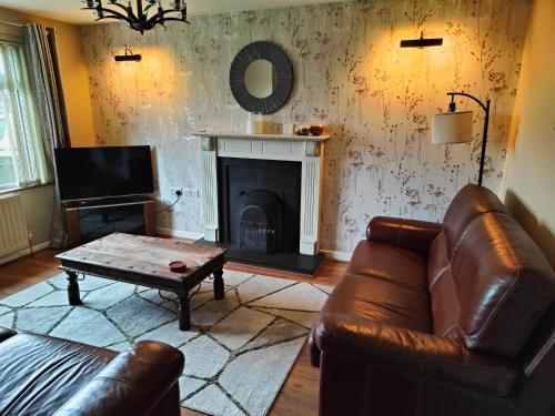 ein Wohnzimmer mit einem Ledersofa und einem Kamin in der Unterkunft Molly's Cottage in Glenariff