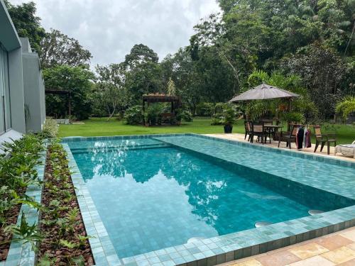 a swimming pool in a yard with a table and an umbrella at Residência Executiva de Alto Padrão - COP30 in Benevides