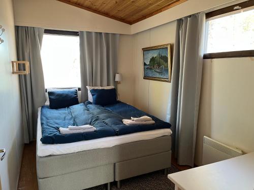 a bedroom with a bed with blue sheets and a window at Two bedroom duplex with peaceful views in Jyväskylä
