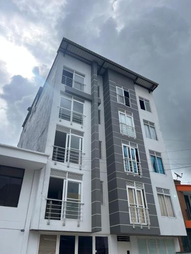 a tall white building with windows on it at Tayra Living Suites in Mocoa