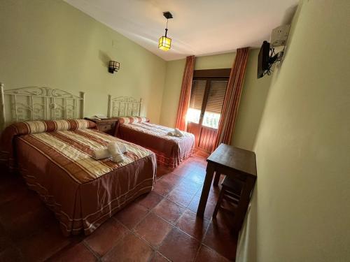 una camera da letto con due letti, un tavolo e una sedia di Hotel Rural Cristina a Castañar de Ibor