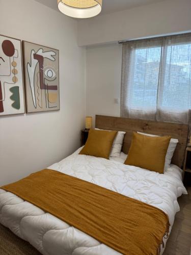 - une chambre dotée d'un grand lit avec des draps blancs et des oreillers bruns dans l'établissement Kazanou, à Cannes