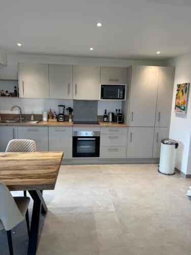 une cuisine avec des armoires blanches et une table en bois dans l'établissement Kazanou, à Cannes