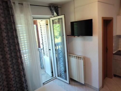a room with a sliding glass door and a television at Apartmani Mila-Casa Bianca in Medulin