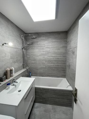 une salle de bain avec une baignoire blanche et un lavabo dans l'établissement grand appartement 74m2 refait à neuf à 5mn de la mer dans grand parc botanique, à Villeneuve-Loubet