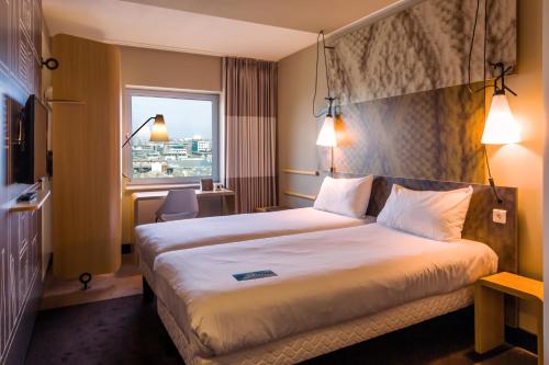 a hotel room with a large bed and a window at ibis Amsterdam City West in Amsterdam