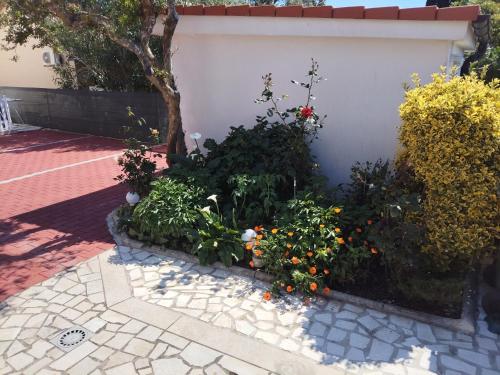 a garden with flowers and plants next to a wall at Apartmani Mila-Casa Bianca in Medulin