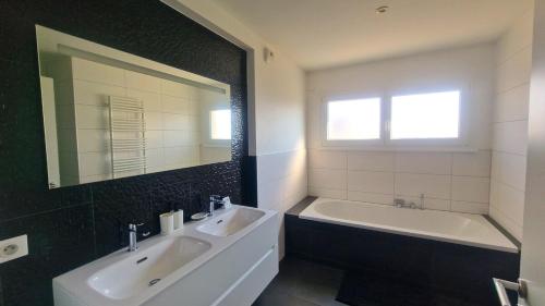 une salle de bain avec deux lavabos, une baignoire et un miroir dans l'établissement Exceptional Border Villa, à Village-Neuf