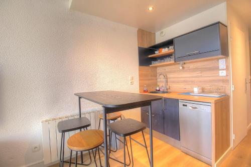 une cuisine avec une table et des tabourets dans une pièce dans l'établissement Cosy 2 pièces dans résidence avec piscine, à Antibes