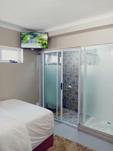 a bedroom with a bed and a glass shower at BKaap2 Queens and Kings Guest House in Cape Town