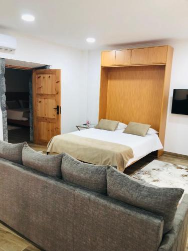 a bedroom with a bed and a couch at AMU- Apartamentos Mistérios da Urzelina in Urzelina