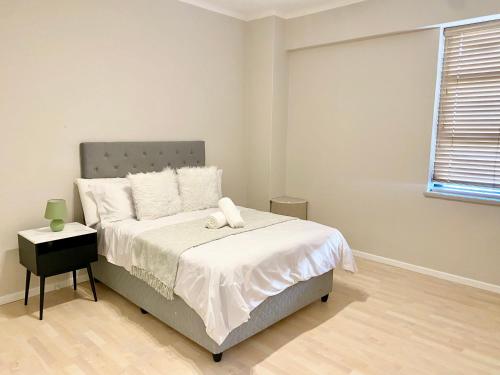 a bedroom with a bed with white sheets and a window at One Bed At The Piazza on Church in Cape Town