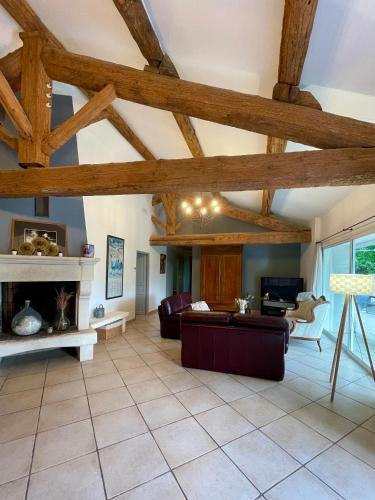a living room with wooden ceilings and a fireplace at Authentique Mas provençal entre mer et Camargue in Marsillargues
