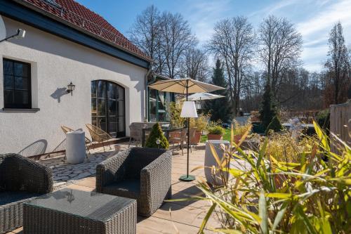 a patio with chairs and an umbrella at Ferienhof am Trift in Bad Saarow