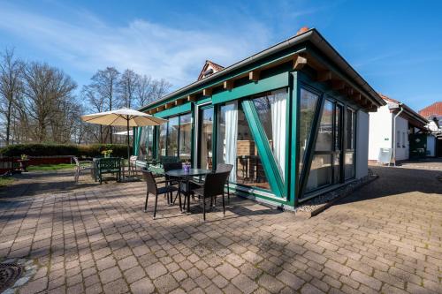 a pavilion with a table and chairs and an umbrella at Ferienhof am Trift in Bad Saarow